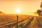 Young woman in the winter jacket with camera on the road against the background of the sunrise autumn field.