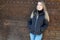 Young woman in winter standing in city wooden background smiling and looking at the camera