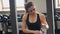 Young woman wipe sweat after exercise sitting on bench in gym.