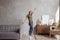 Young woman with wireless headphones dancing and listening to music at home