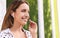 Young woman with wireless headphones listening to music near green grass wall