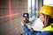 Young woman worker with laser on the building site.