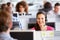 Young woman working in call centre, surrounded by colleagues