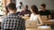 Young woman working in coworking space talking to african-american colleague