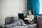 Young woman working at home during quarantine. Sick woman wearing face mask with laptop, lying on sofa. Remote office, self-