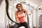 Young woman working out with battle ropes at a gym