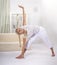 Young woman working out at home in living room. Teenager girl doing yoga or pilates exercise. Full length portrait