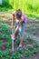 A young woman works in a vegetable garden, weeding potatoes on a summer day.
