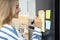 Young woman writing To do list on refrigerator in kitchen