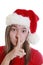 Young woman with xmas hat signalling silence