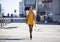 Young woman in yellow dress crossing the road outside