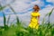A young woman in a yellow dress enjoys a walk in a green field and breathes fresh air in good summer weather