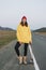 Young woman in yellow hoodie and red hat on skateboard on the road against beautiful mountain landscape, Chuysky tract, Altai
