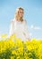 Young woman in yellow oilseed rape field posing in white dress