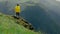 A young woman in a yellow raincoat climbs the slope and enjoys the magnificent scenery of the mountainous areas. Tourism