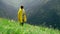 A young woman in a yellow raincoat climbs the slope and enjoys the magnificent scenery of the mountainous areas. Tourism