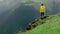 A young woman in a yellow raincoat climbs the slope and enjoys the magnificent scenery of the mountainous areas. Tourism