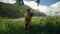 A young woman in a yellow raincoat stands in a meadow with a bouquet of flowers and enjoys the scenery in mountainous