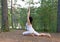 Young woman in Yoga one legged king pigeon pose in the forest