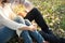 young woman and young man huging and holding bouquet white flower sitting in public garden