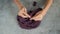 Young womans hands knitting with gray metal needles and dark red cotton thread on stone table background