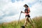 Young women active trail running across a meadow on a grassy trail high in the mountains in the afternoon with trekking pole