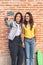 Young women couple making a selfie. Behind brick wall. Positive emotion and tolerance concept