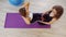 Young women doing fitness in the studio. A woman pumping her abs laying on the purple yoga mat while another woman