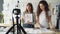 Young women fashion bloggers recording video blog about ladies`clothes on camera and talking to followers in modern