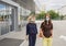 Young women, friends, colleagues, sisters in medical masks on street near building of shopping center or office cente