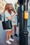 Young women girls buying parking ticket using park machine