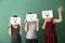 Young women hiding faces behind sheets of paper with drawn emoticons on color background