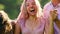 Young women and man in wet clothes and colorful powder laughing at Holi party