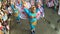 Young women in ornate butterfly costume dance along the street, a festival to honor a patron saint