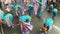 Young women in ornate butterfly costume dance along the street, a festival to honor a patron saint