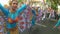 Young women in ornate butterfly costume dance along the street, a festival to honor a patron saint