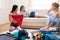 Young women packing suitcases for vacation together at home