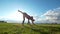 Young women performs gymnastic elements on the grass at summer sunset