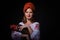 Young women in the red kokoshnik holding cock bird on black background. Russian fairytale.Studio shot