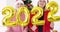 Young women in red santa claus hats smiling and waving golden balloons with numbers 2022 4k movie