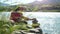 Young women relaxing on nature putting pebble stack next to the mountain river