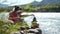 Young women relaxing on nature putting pebble stack next to the mountain river