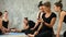 Young women relaxing, using smartphone, talking after workout at yoga class