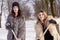 Young women shoveling snow near a small wood