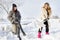 Young women shoveling snow near a small wood