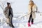 Young women shoveling snow near a small wood