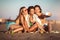 Young women sitting on the beach using phone,make selfie. Group of friends enjoying on beach, selective focus