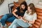 Young women with smartphone and notepad. Casual girlfriends sitting on leather sofa with notebook