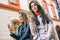 Young women standing in a urban area using mobile phone in the city - Happy friends connecting on social media network outdoor