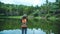 Young women travel nature. She stands waterfront at the public park Photographing beautiful landscape